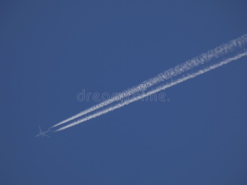 Plano sulcando o céu azul e deixando uma vigília branca fotografia de stock Plano sulcando o céu azul e deixando uma vigília branca fotografia de stock