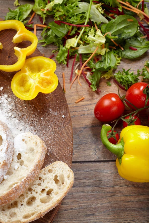 Plantaardige ingrediënten en gesneden brood op een scherpe raad royalty-vrije stock afbeelding Plantaardige ingrediënten en gesneden brood op een scherpe raad royalty-vrije stock afbeelding