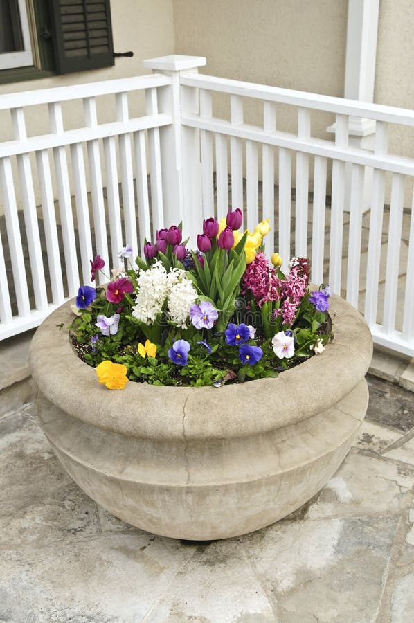 Stone planter with spring flowers on house patio. Stone planter with spring flowers on house patio