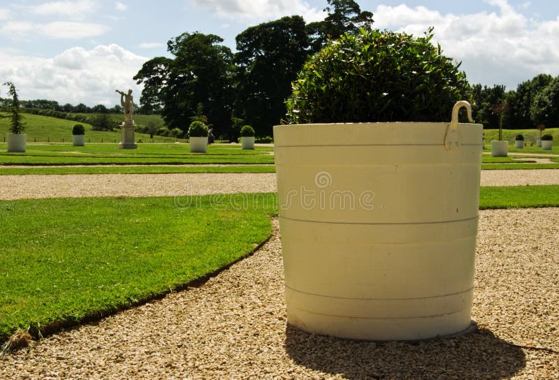A large painted planter with plan in the context of a beautiful landscaped garden. A large painted planter with plan in the context of a beautiful landscaped garden.