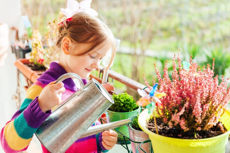 Menina a regar plantas na varanda imagem de stock