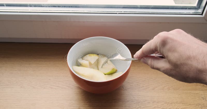 Plaque avec tranches de poire hachées. une main d'homme prend une pièce avec une fourchette. point de vue. fenêtre de fermeture de banque de vidéos
