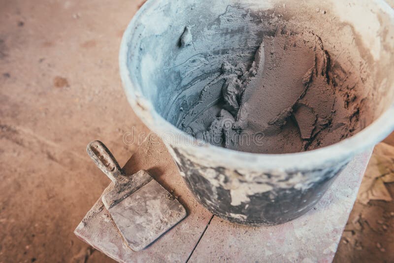 Plaster inside bucket with putty knive for wall renovation