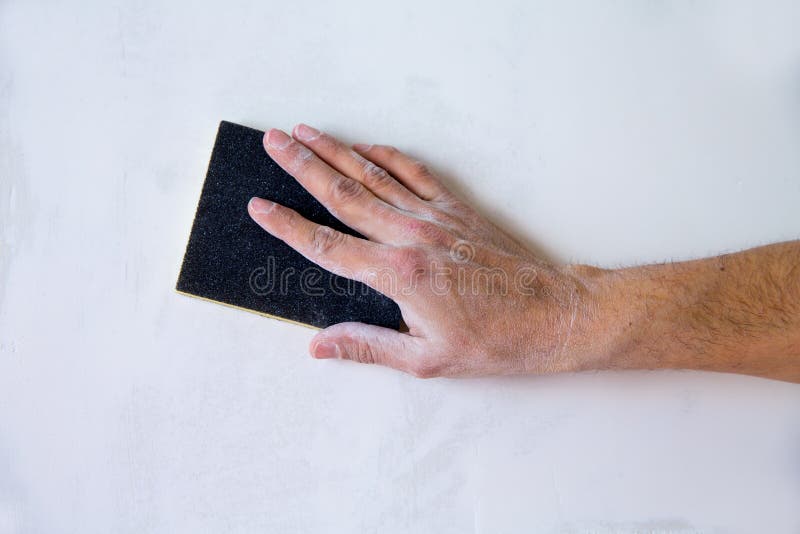 Plastering man hand sanding the plaster