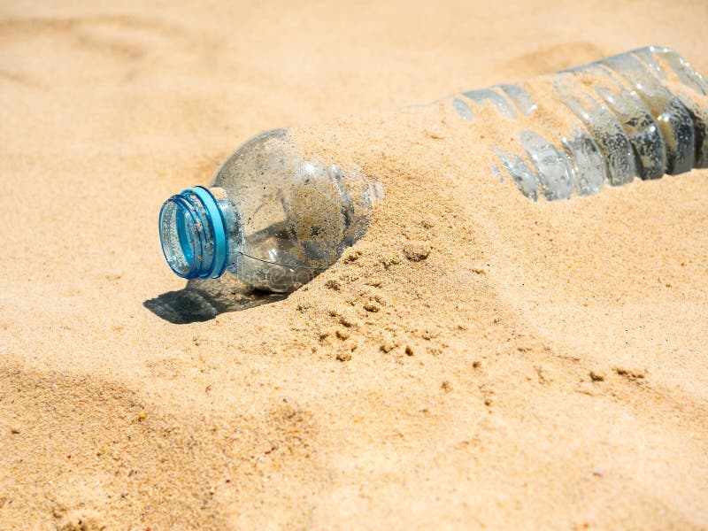 Plastic bottle on sandy beach. Close-up empty uncapped used plastic drinking water bottles piled up with sand, dumped on the beach. Polluted garbage abandoned by tourists. Plastic bottle on sandy beach. Close-up empty uncapped used plastic drinking water bottles piled up with sand, dumped on the beach. Polluted garbage abandoned by tourists.