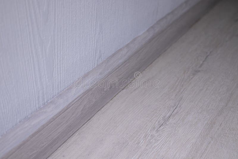 Plastic Baseboard between the Gray Structural Wall and Woodlike