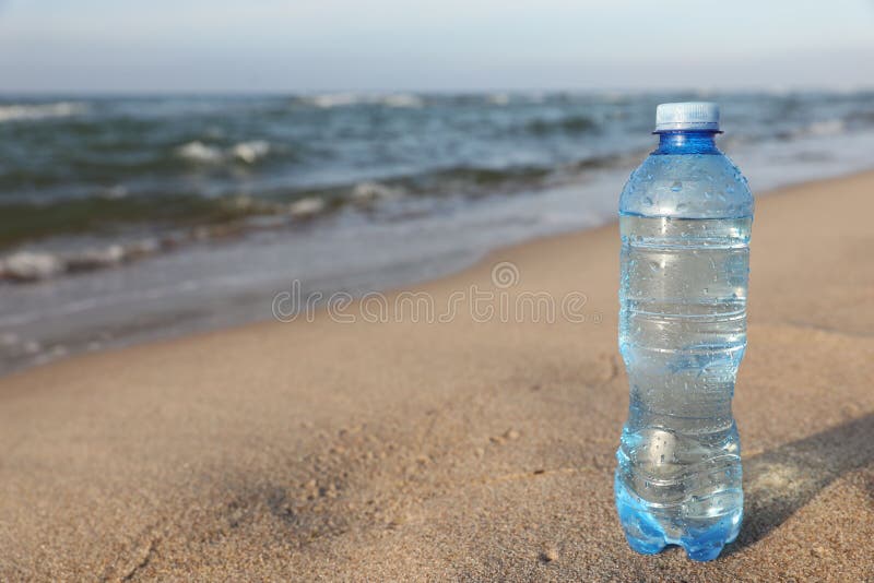 Plastic Bottle of Fresh Water on Wet Sand Near Sea. Space for Text