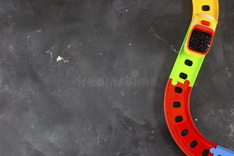 Plastic bright toy truck on curved road on black chalkboard background with copy space. Top view. Creative concept for transport royalty free stock image Plastic bright toy truck on curved road on black chalkboard background with copy space. Top view. Creative concept for transport royalty free stock image