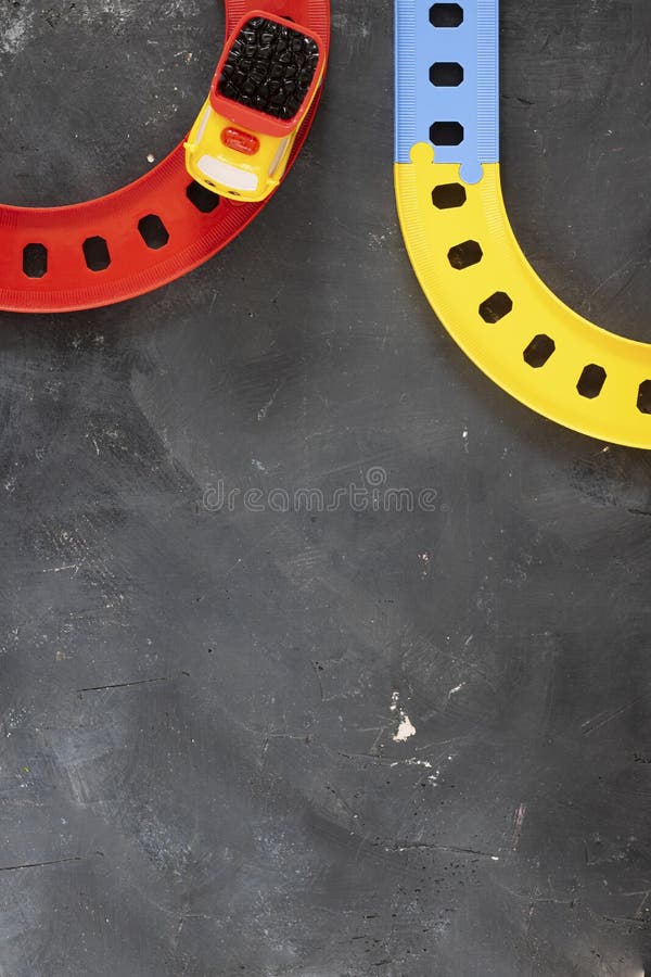 Plastic bright toy truck on curved road on black chalkboard background with copy space. Top view. Creative concept for transport stock images Plastic bright toy truck on curved road on black chalkboard background with copy space. Top view. Creative concept for transport stock images