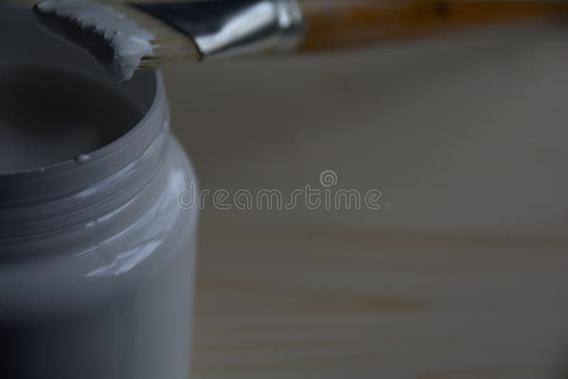 Plastic Can with White Acrylic Primer and a Bristle Brush on a Wooden