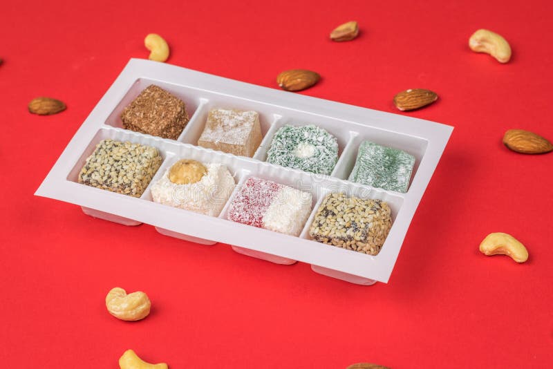 A Plastic Container with Turkish Delight and Nuts on a Red Table Stock