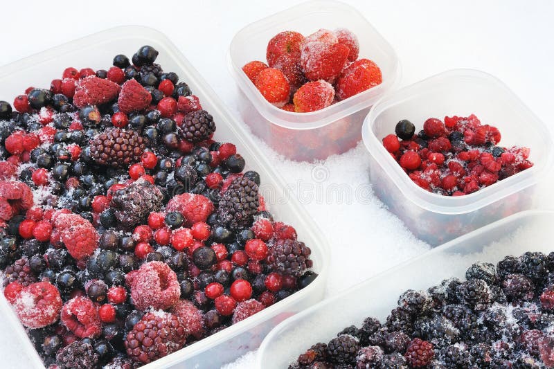 Plastic containers of frozen mixed berries in snow