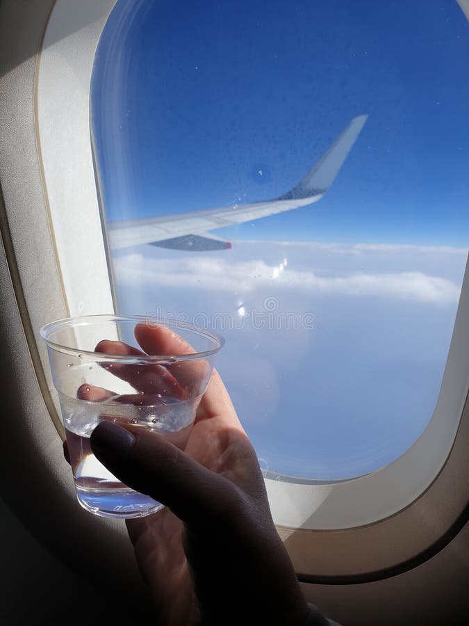 Plastic Cup of Water on the Hand in the Plane during the Flight Stock