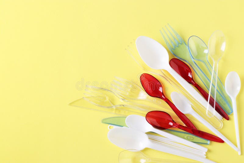 Plastic Cutlery, Forks, Spoons and Knives on Yellow Background. Pollution of the Environment