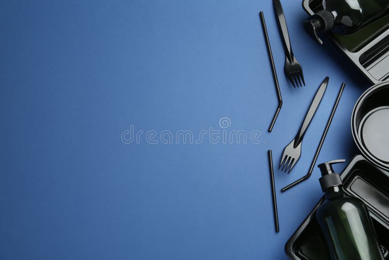 Plastic dishware and dispenser on blue background, flat lay. Space for text