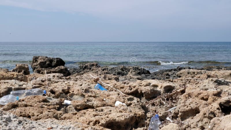 Plastic flessen die op het rotsachtige verontreinigde strand liggen Milieuproblemenconcept