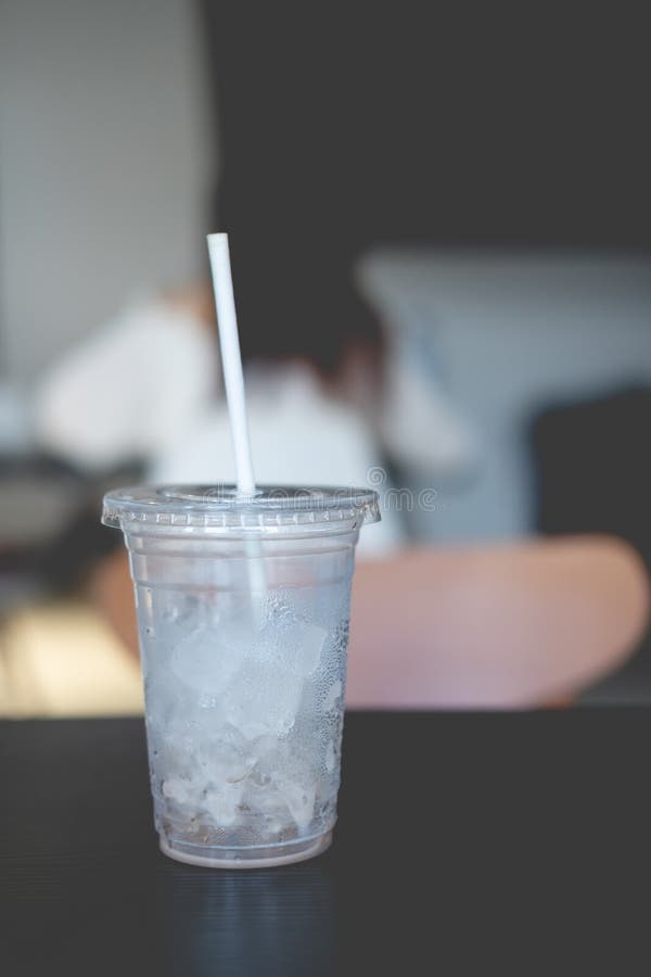 Plastic glass with ice cube on wood table