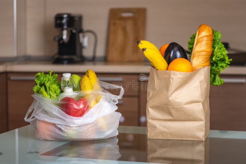 Plastic and paper bags with food on the kitchen table. Choosing the use of environmental packaging and plastic rejection stock images