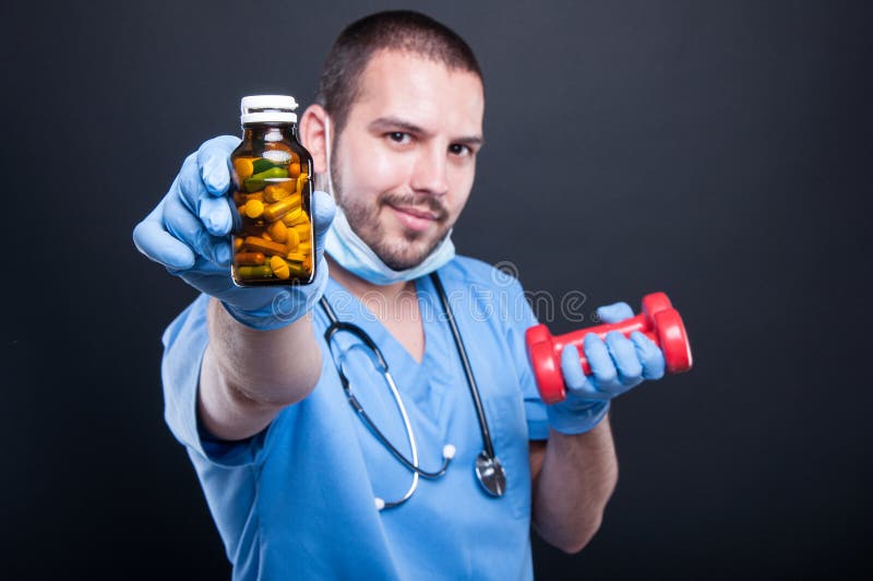 Plastic surgeon showing pills to choose before dumbbells royalty free stock image
