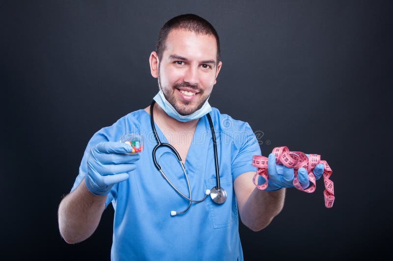 Plastic surgeon wearing scrubs holding measuring tape and pills stock photo