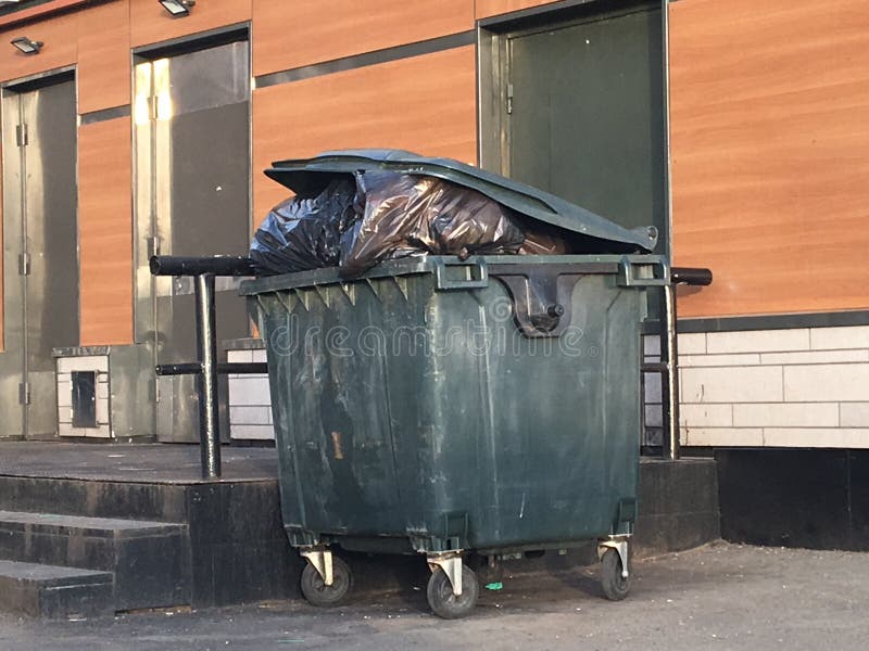 Plastic Trash Can with Waste on the Street. Garbage Can Stock Photo