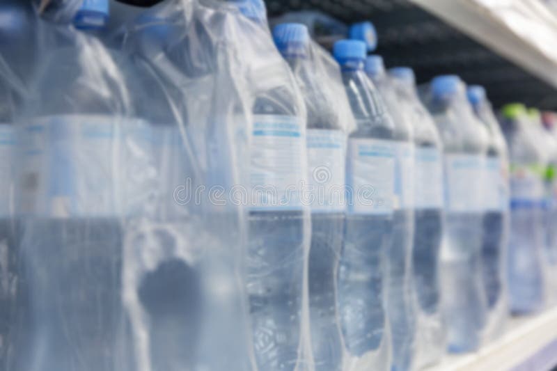 Plastic Water Bottles in Packaging on a Shelf in a Store. Blurred Stock