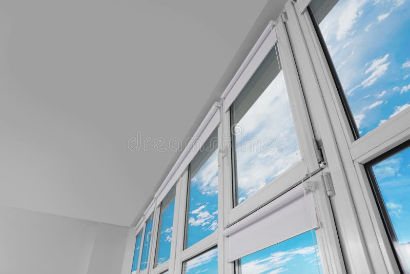 Plastic Windows with White Roller Blinds Indoors, Low Angle View Stock