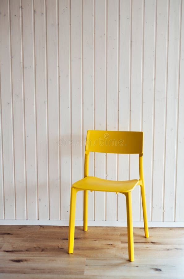 A Plastic Yellow Chair Against White Wood Texture Background. Stock
