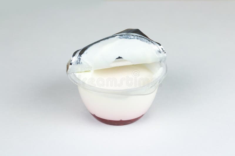 Plastikglas mit einer offenen Deckelfolie, einem natürlichen weißen Jogurt und einem roten Stau lizenzfreie stockfotos Plastikglas mit einer offenen Deckelfolie, einem natürlichen weißen Jogurt und einem roten Stau lizenzfreie stockfotos