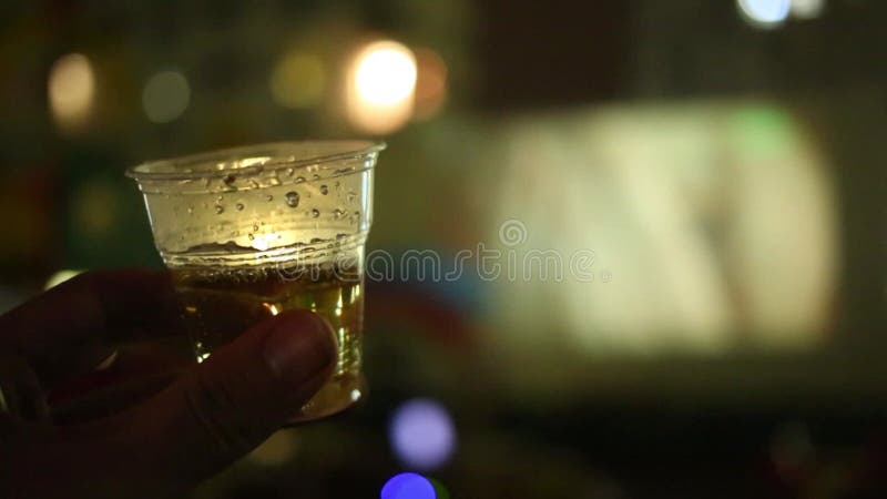 Plastikowy kubek z napojem w męskiej ręce na zbiory