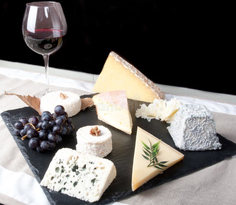 Plat de fromage avec le vin rouge, la vigne et le miel sur le fond noir photographie stock Plat de fromage avec le vin rouge, la vigne et le miel sur le fond noir photographie stock