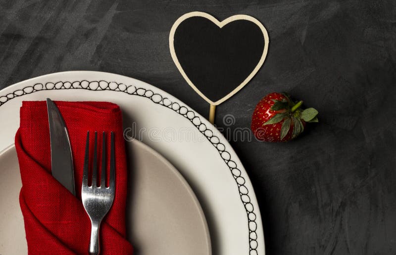 Plat de portion de Saint-Valentin avec la fourchette, le couteau et la carte vierge en forme de coeur d'endroit au fond noir photo libre de droits Plat de portion de Saint-Valentin avec la fourchette, le couteau et la carte vierge en forme de coeur d'endroit au fond noir photo libre de droits
