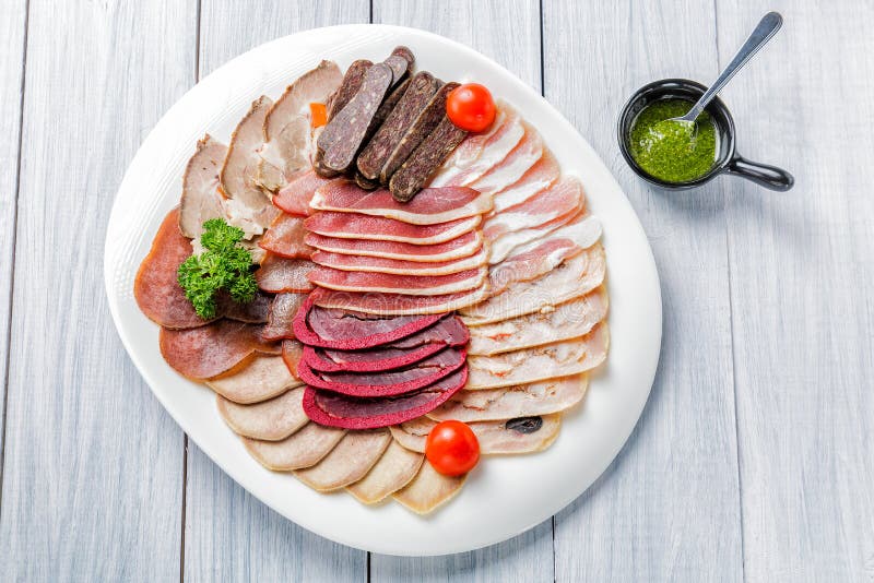 Plat de viande avec les morceaux délicieux de jambon, de tomates-cerises, d'herbes, de viande et de sauce coupés en tranches Vue photos stock Plat de viande avec les morceaux délicieux de jambon, de tomates-cerises, d'herbes, de viande et de sauce coupés en tranches Vue photos stock