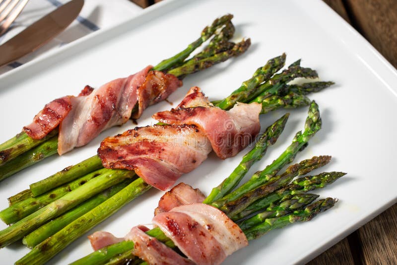 Cooked asparagus with wrapped bacon on plate