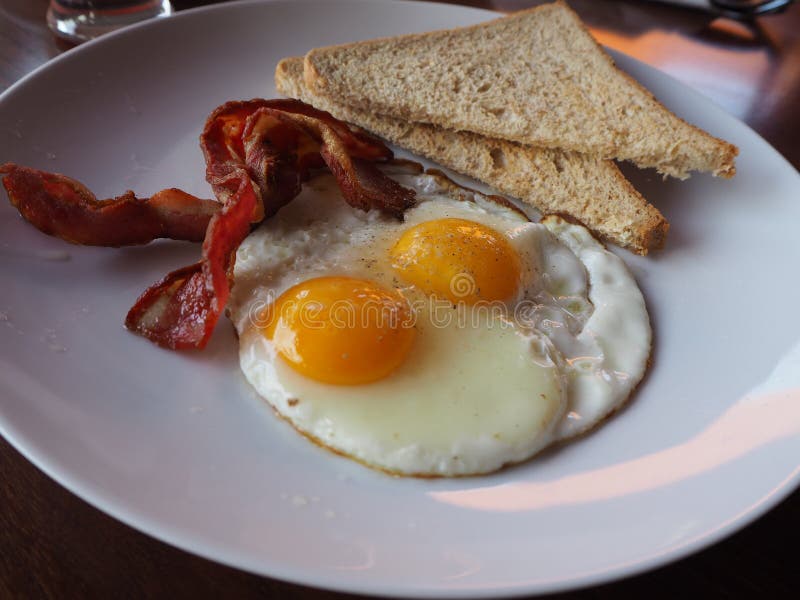 Plate of Breakfast with Fried Eggs, Bacon and Toasts Stock Photo