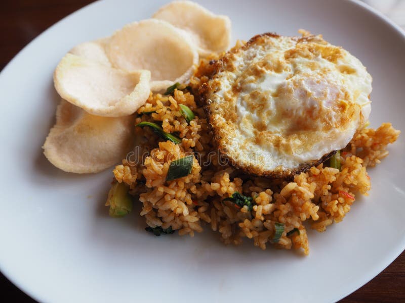 Fried rice, fried eggs, shrimp rice cracker on white dish