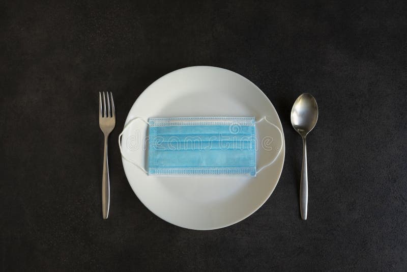Plate, cutlery and medical mask as a symbol of the end of social isolation