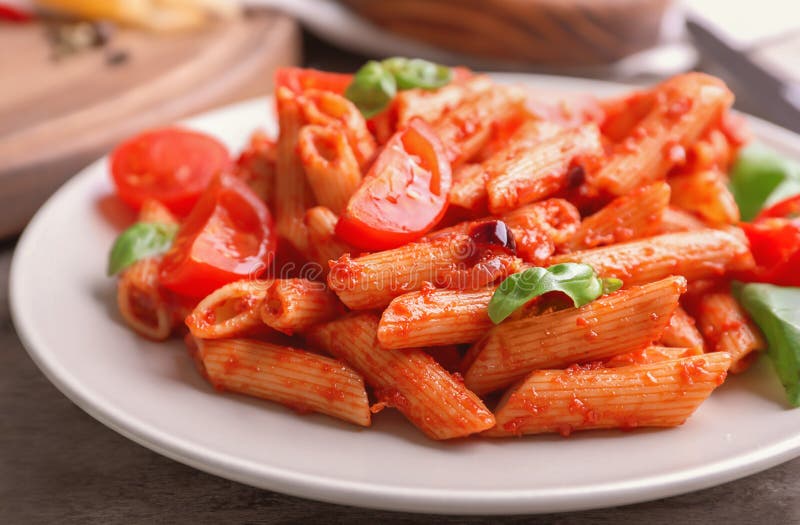 Plate with Delicious Penne Pasta and Garnish on Table, Closeup Stock
