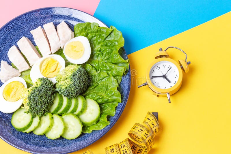 A plate with food on pink and blue background, interval fasting concept stock photography