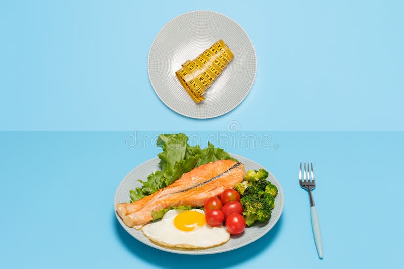 Plate of food and plate with tape measure on blue background, intermittent fasting concept. stock images