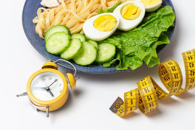 Plate with food on white background and alarm clock, a interval fasting concept stock photo