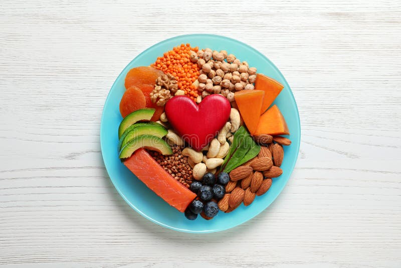 Plate with heart-healthy products on wooden background