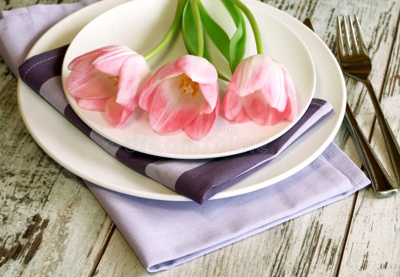 Plate, knife, fork and tulips on wooden