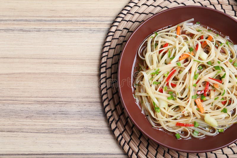 Plate of Noodles with Broth and Vegetables on Table, Top View Stock
