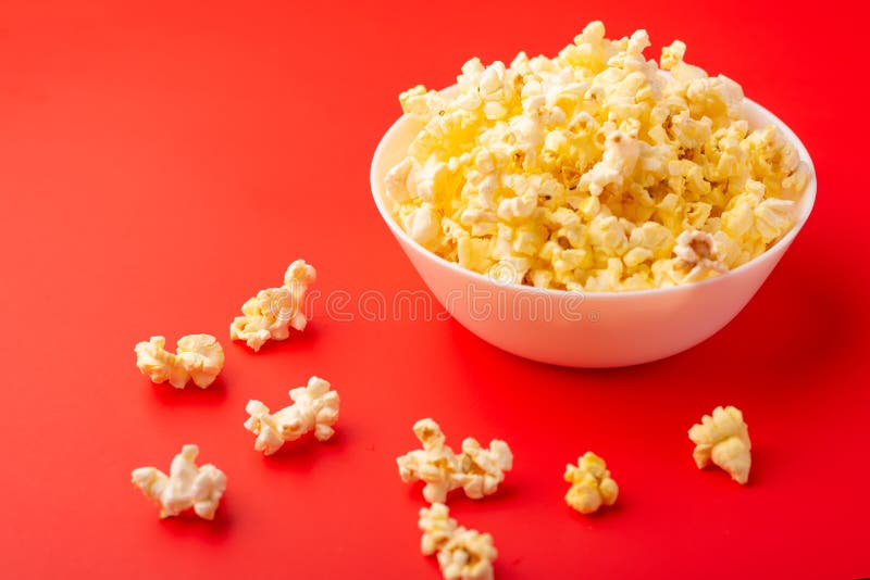Plate with popcorn on a red bright background. movie viewing concept, weekend getaway, with space royalty free stock photo Plate with popcorn on a red bright background. movie viewing concept, weekend getaway, with space royalty free stock photo