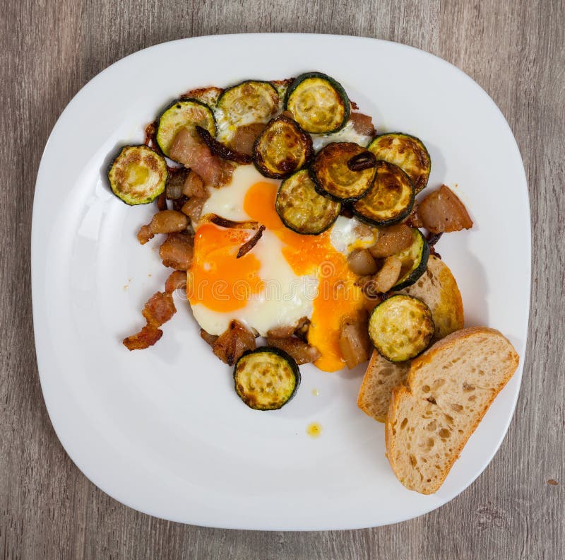 Plate with Scrambled Eggs with Lard and Zucchini at Table on Table
