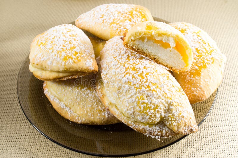 Plate with sweet pastries sprinkled with icing sugar powder