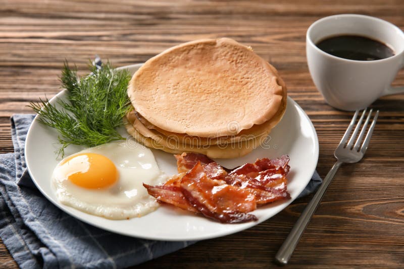 Plate with Tasty Pancakes, Fried Egg and Bacon on Wooden Table Stock