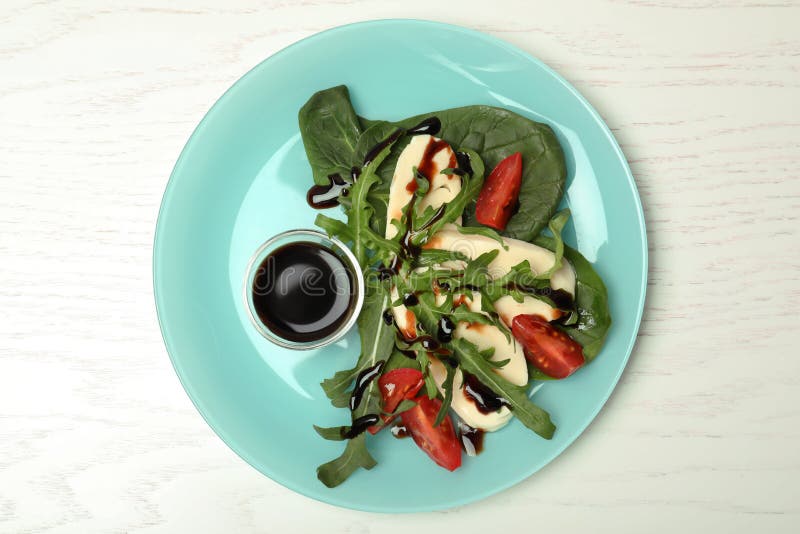 Plate with vegetable salad and balsamic vinegar on white wooden table