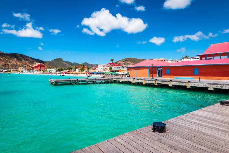 Colorful image of Philipsburg, St Maarten Sint Maarten, Saint Martin, Caribbean. Wooden dock and colorful buildings at Great Bay beach. Popular cruise destination. Blue sky and white clouds on a beautiful summer day. Colorful image of Philipsburg, St Maarten Sint Maarten, Saint Martin, Caribbean. Wooden dock and colorful buildings at Great Bay beach. Popular cruise destination. Blue sky and white clouds on a beautiful summer day.